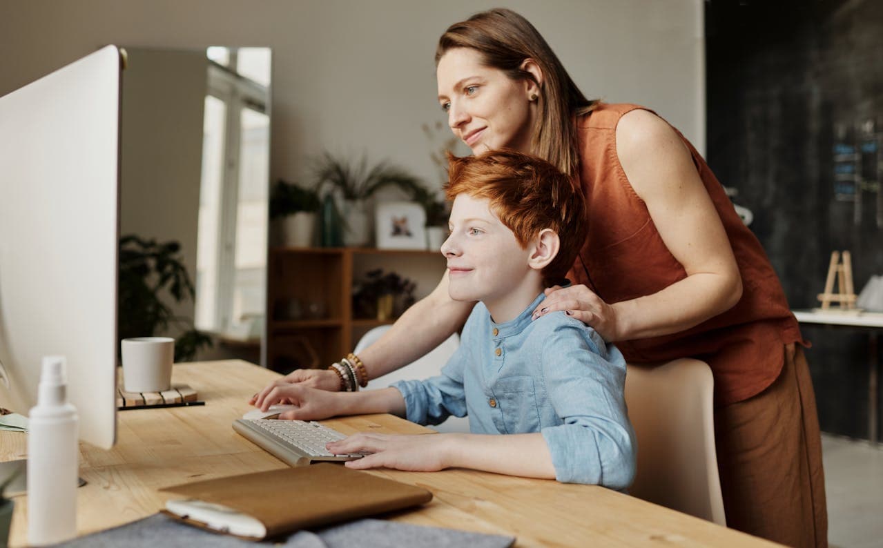 Teacher or parent supporting a student at a computer
